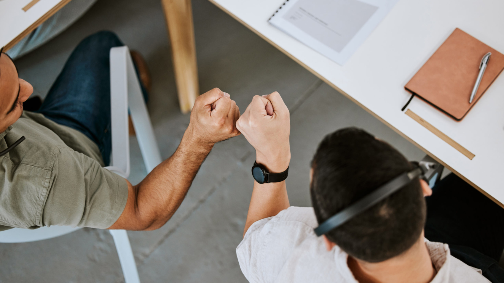 Excited call centre agents, fist bump and celebrating deal, promotion and sale from above in office. Motivated, happy and successful telemarketing colleagues or customer support operators cheering